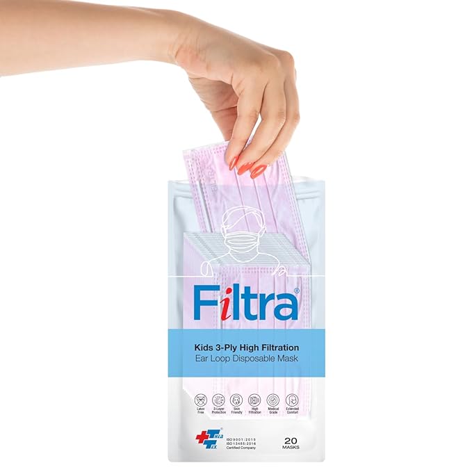 A woman's hand reaches into a package of FILTRA Kids 3-Ply High Filtration Ear Loop Disposable Masks, which contains 20 pink masks.